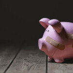 Broken piggy bank with band aid bandage or plaster finance background